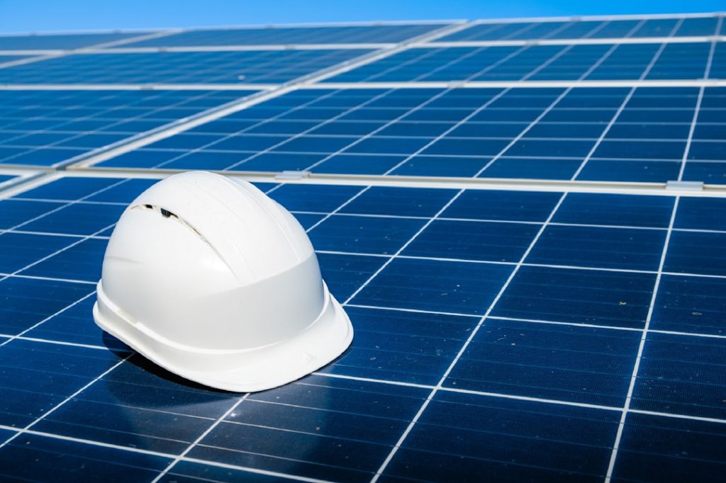 Solar cell contractor document with orange engineering team helmet on solar cells panels. Renewable energy and ecology concept