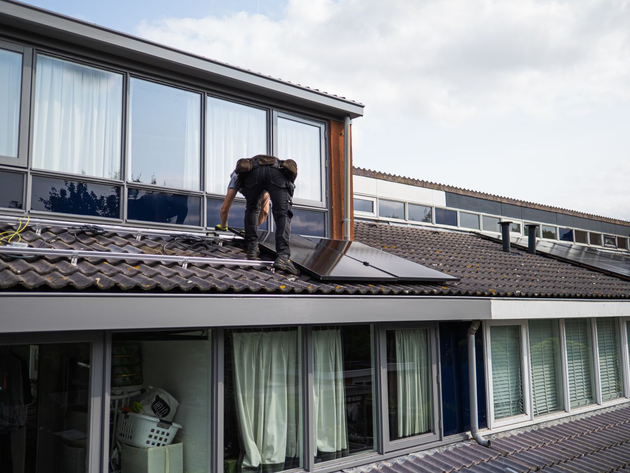 gallery-03 Technician working on installing solar panels on a residential rooftop during the day.